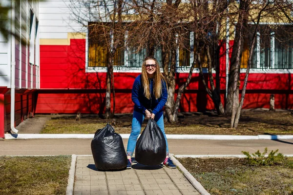 Femeie zâmbitoare care deține pungi mari de plastic cu gunoi — Fotografie, imagine de stoc