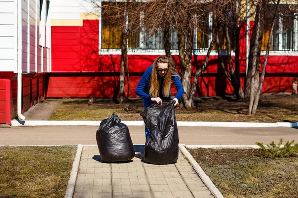 Тридцатилетняя женщина собирает мусор в больших пластиковых пакетах — стоковое фото