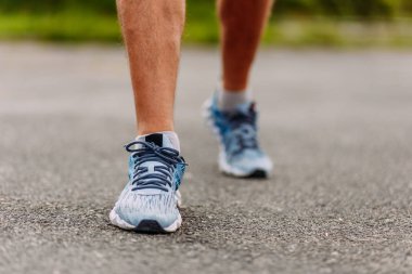 running shoes on men's feet on asphalt clipart