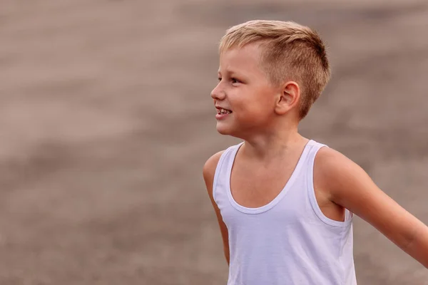 Улыбающийся блондин в белой хлопчатобумажной футболке на открытом воздухе на размытом летнем фоне — стоковое фото