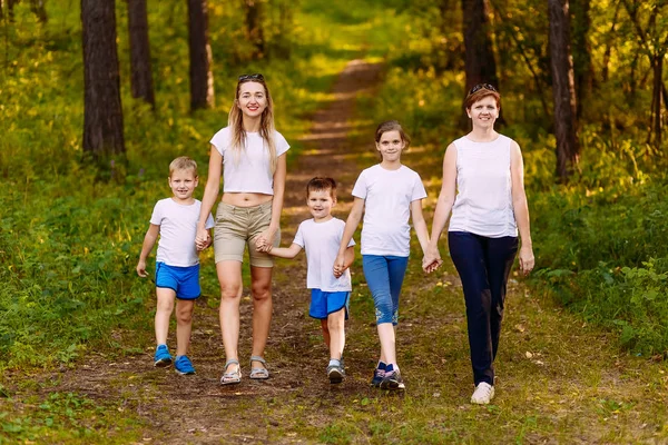Madres sonrientes y niños tomados de la mano. Gran familia feliz, dos mujeres y tres niños en camisetas blancas — Foto de Stock