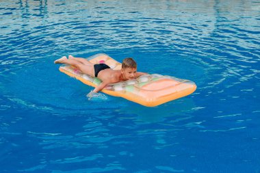 Çocuk açık yüzme havuzunda şişme yatak üzerinde yüzer