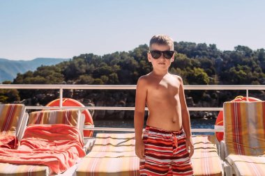 Güneş gözlüklüğü çocuk bir yat üzerinde duruyor