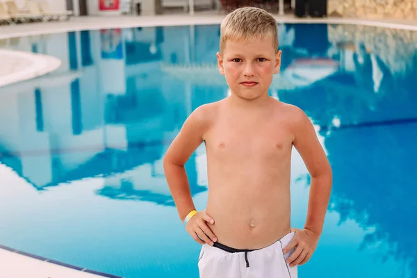 Семилетний мальчик стоит у открытого бассейна — стоковое фото