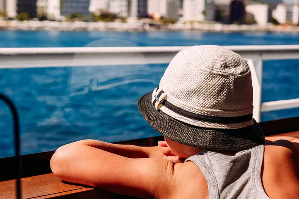 Мальчик в белой шляпе смотрит на море через окно корабля . — стоковое фото