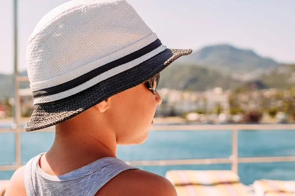 En pojke i en vit hatt som tittar på havet. Sommaren — Stockfoto