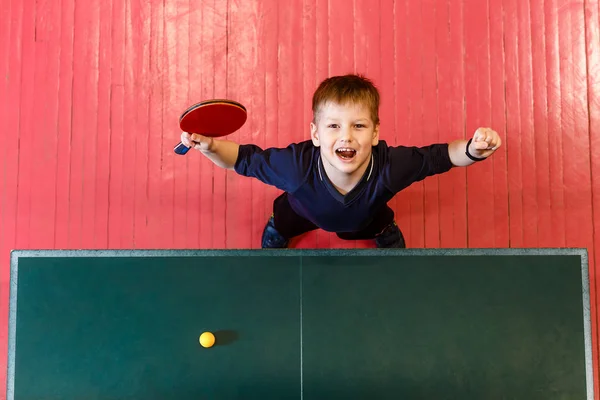 Wesoły siedmioletni dziecko cieszy się zwycięską tenis stołowy, widok z góry. — Zdjęcie stockowe