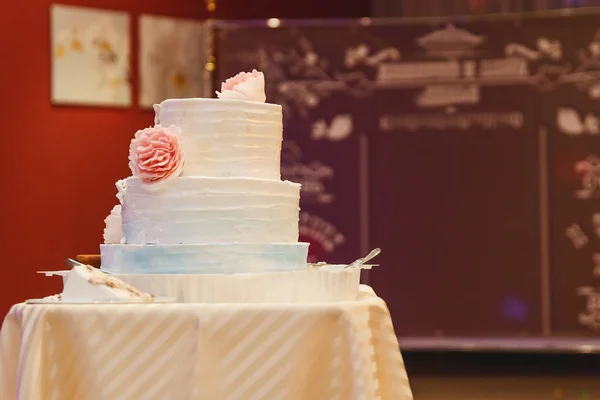 cream three-tiered white cake with pink flowers