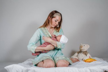 Genç beyaz kadın yeni doğmuş bir bebeği sakinleştiriyor.