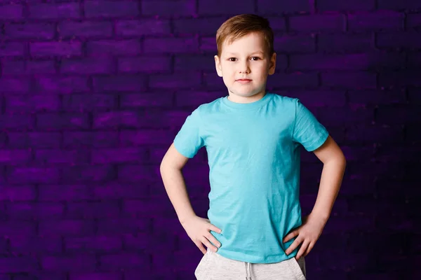 Портрет семилетнего мальчика в бирюзовой футболке и серых брюках — стоковое фото