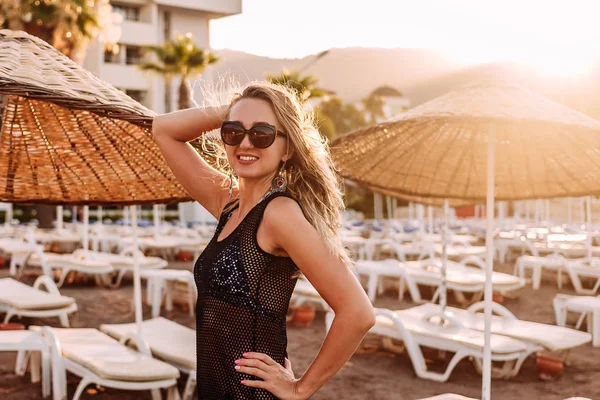 Улыбающаяся молодая женщина, позирующая на пляже в солнечном свете — стоковое фото