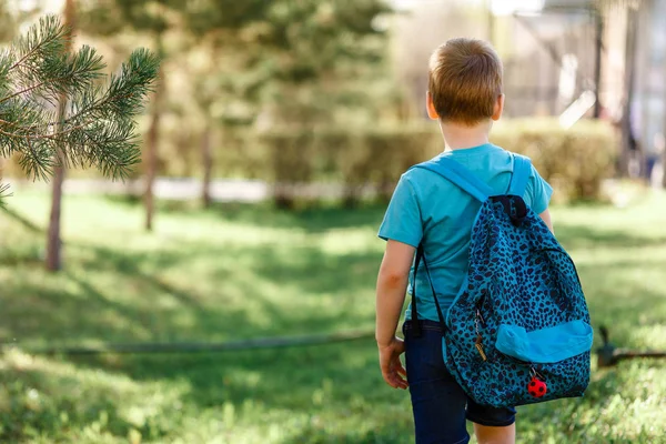 eight-year-old sports boy with a backpack on his back is back in the summer