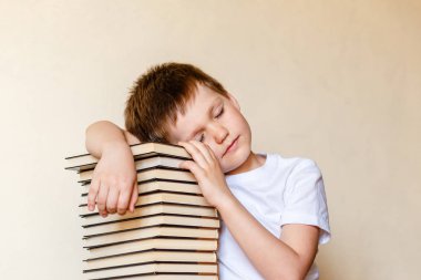 gözleri kapalı kitap yığını üzerinde yatan yorgun esitleti çocuk