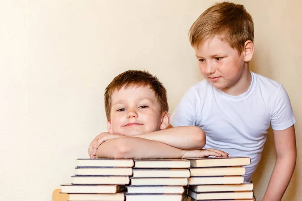 Dwóch chłopców w białych koszulkach przy stole z książkami — Zdjęcie stockowe