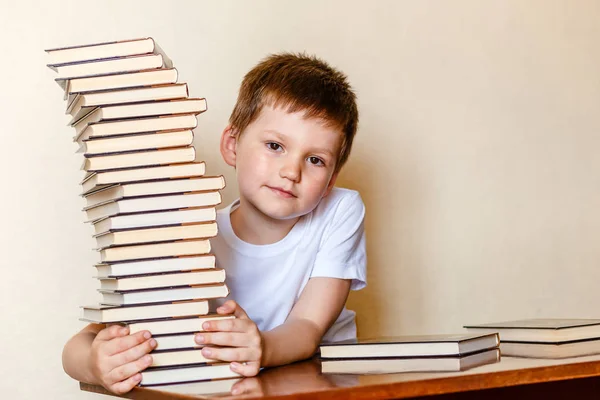 Ragazzo di prima elementare che tiene una grande pila di libri. raccolta di libri — Foto Stock