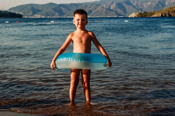 Милый пятилетний мальчик стоит с резиновым надувным кругом в море в Турции — стоковое фото