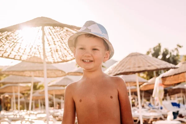 Niño sonriente en la playa en una contraluz puesta de sol —  Fotos de Stock