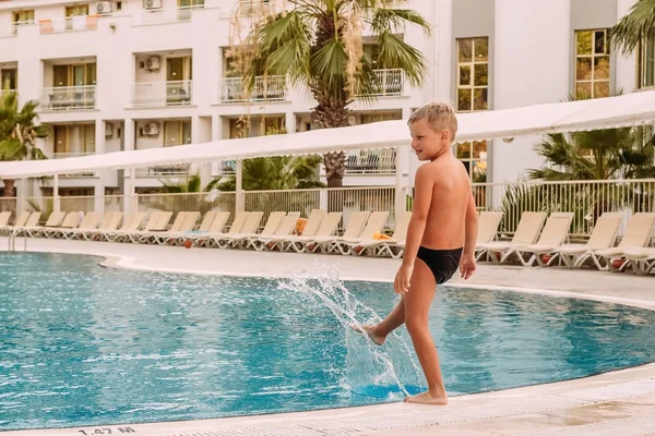 Opalony chłopiec stoi przy odkrytym basenie — Zdjęcie stockowe