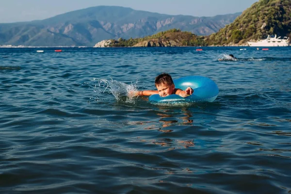 Πεντάχρονο αγόρι σε μια γαλάζια σημαδούρα μαθαίνει να κολυμπάει στη θάλασσα, την Τουρκία — Φωτογραφία Αρχείου