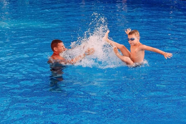 Gelukkig gelooid man leert het kind om te zwemmen in het zwembad. duiken i — Stockfoto