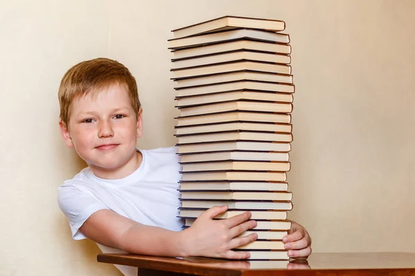 Osiem lat uśmiechnięte dziecko i duży stos książek. dzieci i czytanie — Zdjęcie stockowe