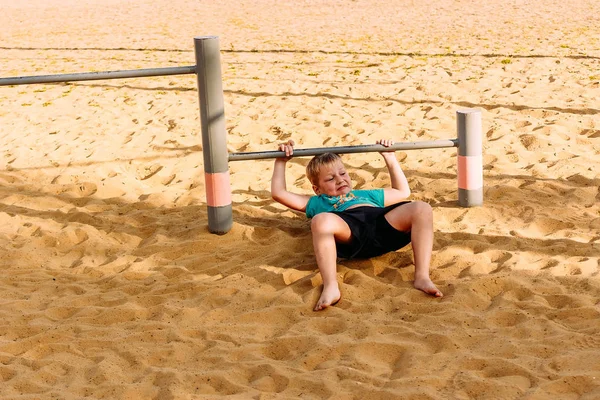 Niño de siete años de edad, se dedica a la calle barras horizontales en la playa —  Fotos de Stock