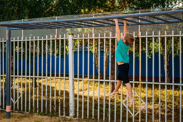 Garçon de sept ans est engagé sur les barres horizontales de la rue — Photo