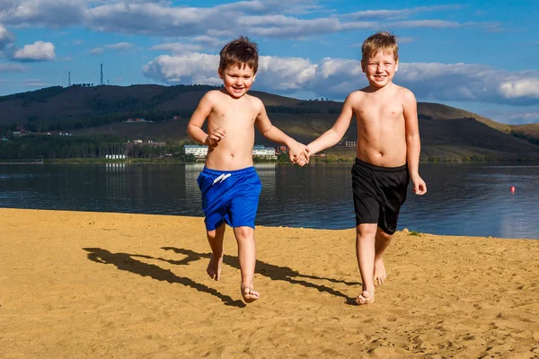 Barnen springer på sanden på stranden — Stockfoto