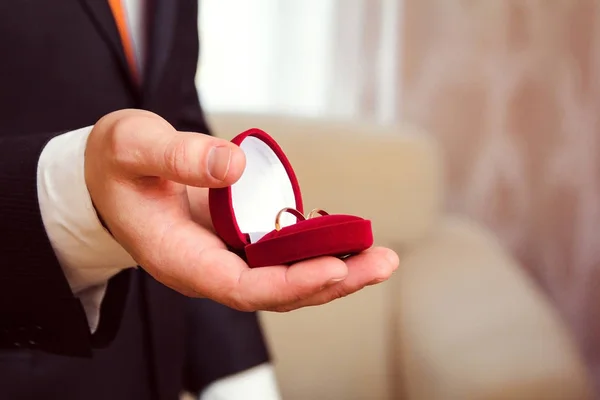 Обручальные кольца в коробке в руке жениха — стоковое фото