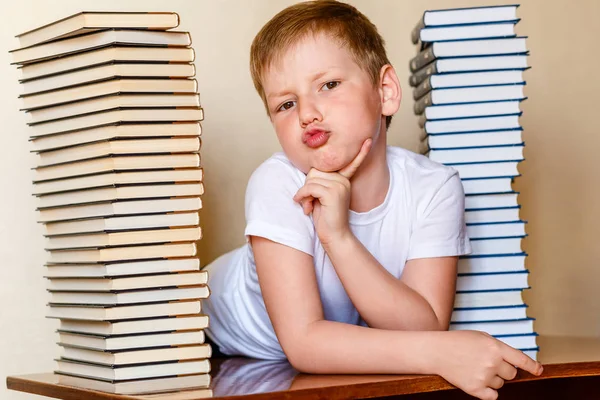 Osiem lat chłopiec w białym t-shirt i wiele książek na stole — Zdjęcie stockowe