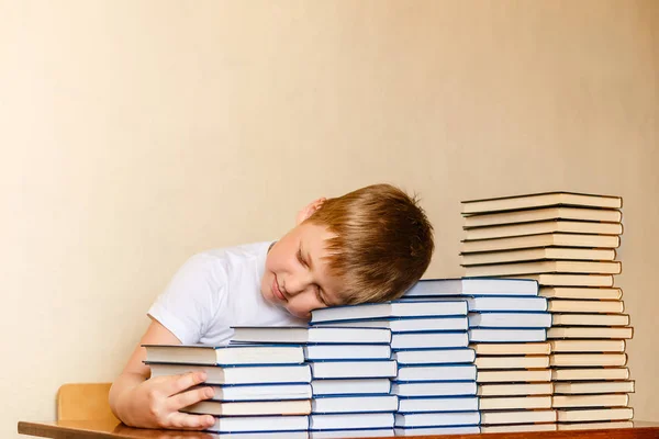 Zmęczony ośmioletni chłopiec śpi na książkach przy stole. dzieci i czytanie. — Zdjęcie stockowe