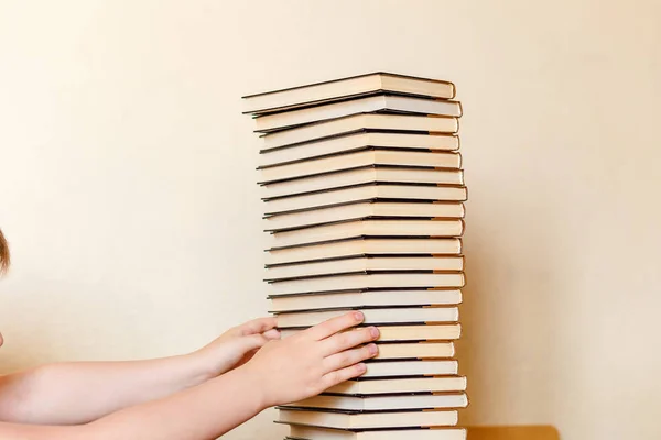 Dziecko wybiera książkę z dużego stosu — Zdjęcie stockowe