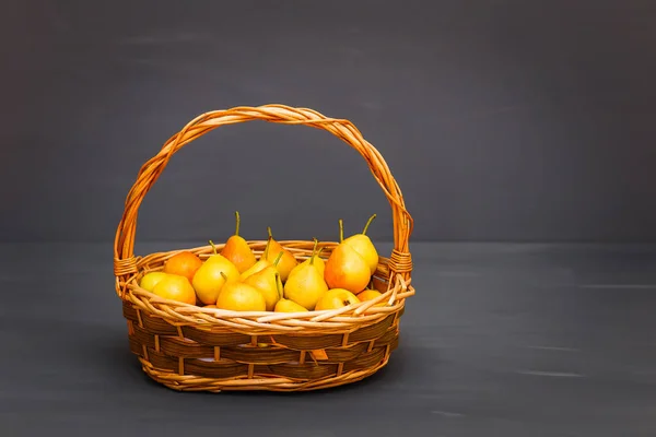 Poires jaunes mûres dans un panier sur un fond gris — Photo