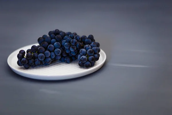 Belas uvas azuis pretas Isabella encontra-se em uma placa branca — Fotografia de Stock