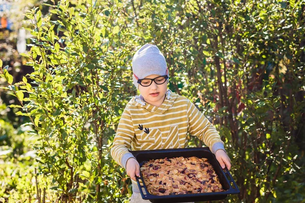 Funny sjuårig kaukasiska pojke innehar en stor fruktkaka på sommaren — Stockfoto