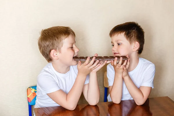 Dva malí kluci koušou velký čokoládový bar — Stock fotografie