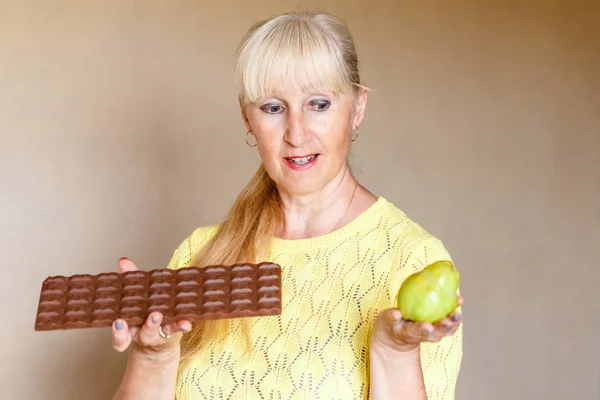 Кавказская женщина с шоколадом и фруктами в помещении, женщина на диете, выбор правильного питания — стоковое фото