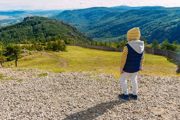 Boy stands with his back on the mountain — Stock Photo, Image