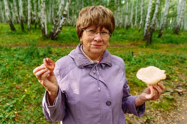 Пожилая женщина с грибами в лесу — стоковое фото