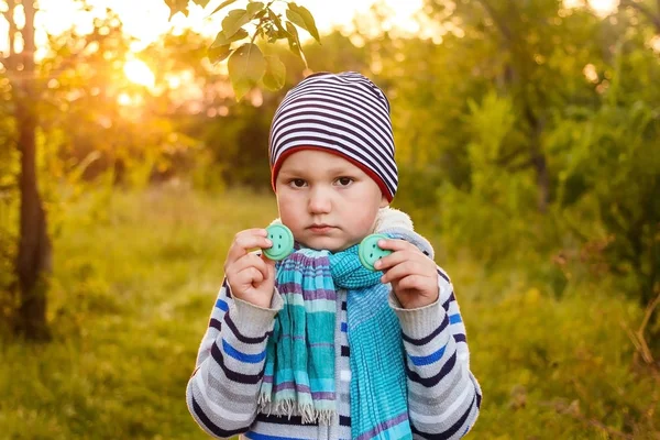 Пятилетний грустный мальчик в полосатой шляпе и с голубым шарфом в руках — стоковое фото