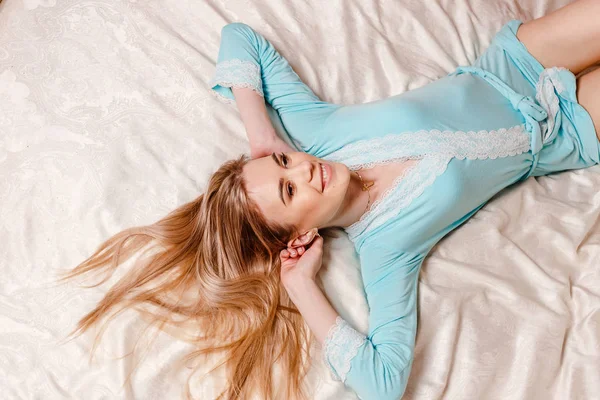 Mujer joven sonriente yace en la cama —  Fotos de Stock