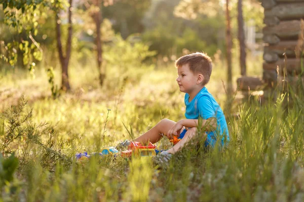 Kaukasiska korthårig pojke sitter i gräset på sommaren — Stockfoto