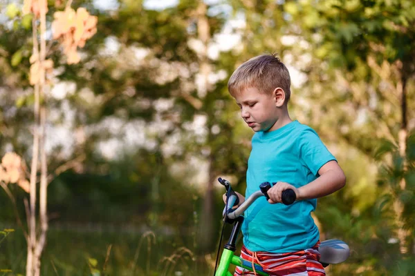 Siedmioletni chłopiec jeździ rowerem na niewyraźne naturalne tło — Zdjęcie stockowe