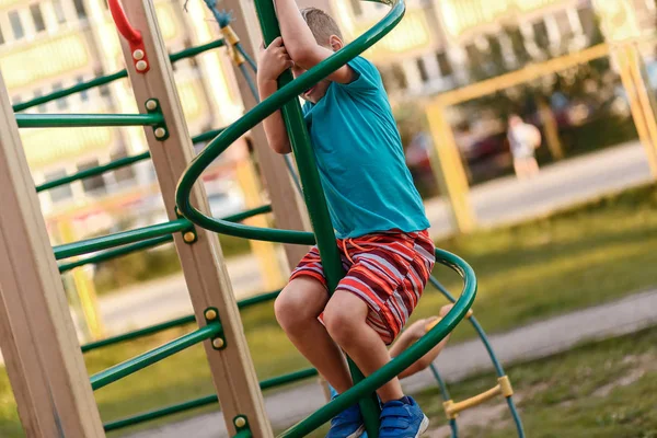 Un niño jugando en el parque infantil cerca de la casa en el verano —  Fotos de Stock
