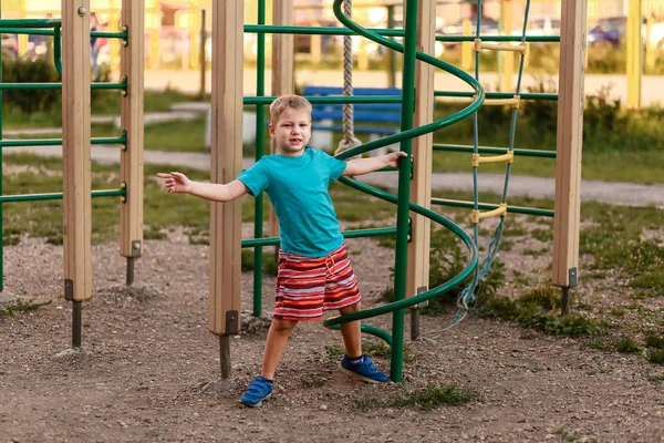 7-летний мальчик в шортах играет летом на детской площадке — стоковое фото