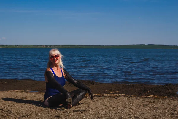 Счастливая пятидесятилетняя женщина в купальнике, испачканном грязью — стоковое фото