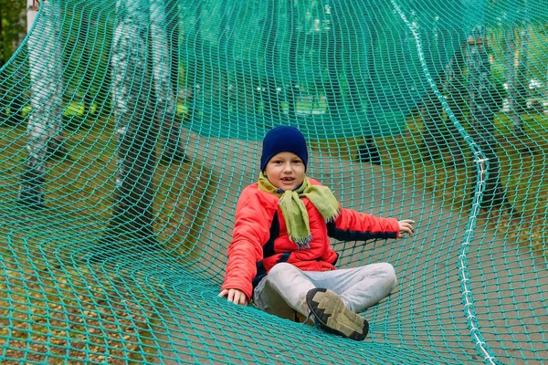 Улыбающийся мальчик на растянутой спортивной сетке — стоковое фото