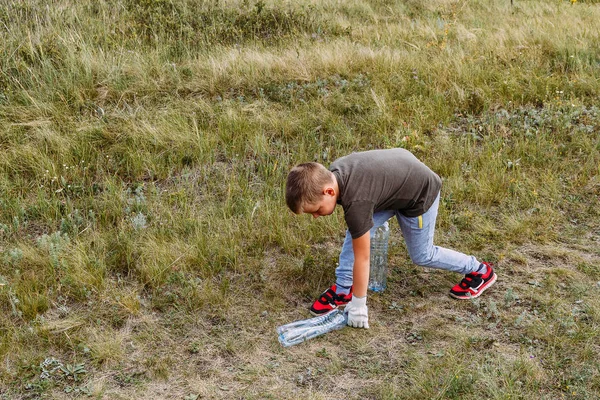 A criança coleta lixo plástico na floresta no verão — Fotografia de Stock