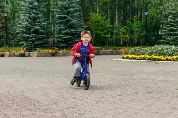 Cheerful five-year-old boy rides a running bike — Stock Photo, Image