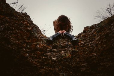 Üzgün bir kadın sonbaharda başı öne eğik kayalıklarda oturur. Yalnızlık.